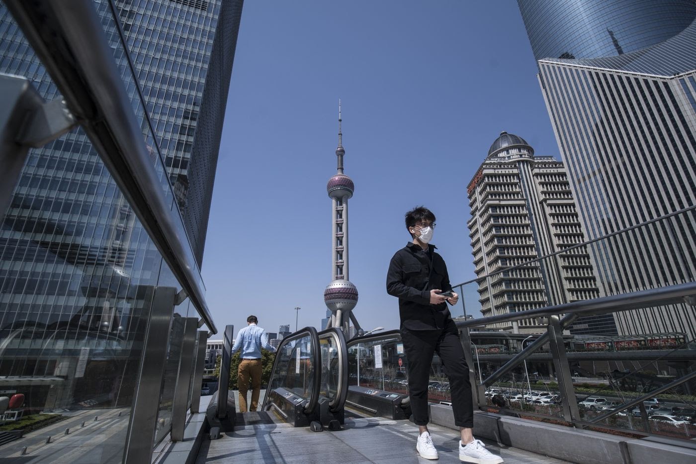 A pedestrian wearing a protective mask walks through the Lujiazui Financial District in Shanghai.